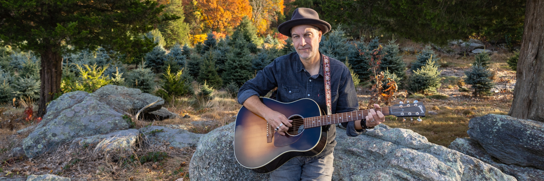 Brian Dolzani sitting on farm rocks in the fall