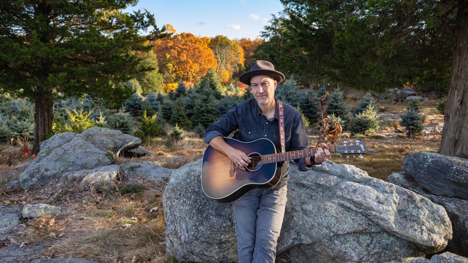 Brian Dolzani sitting on farm rocks in the fall