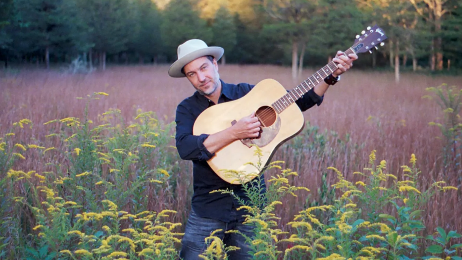 Brian Dolzani on the guitar in a field