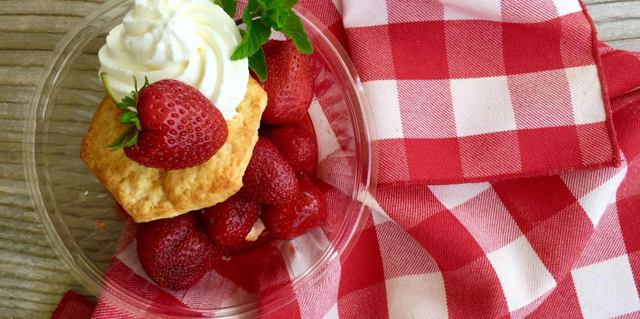 strawberry shortcake on a clear plate over red and white cloth