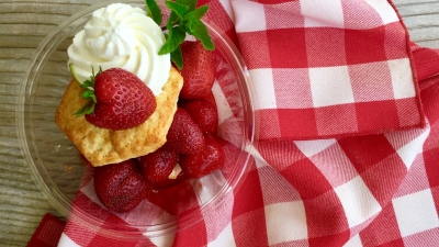 strawberry shortcake on a clear plate over red and white cloth