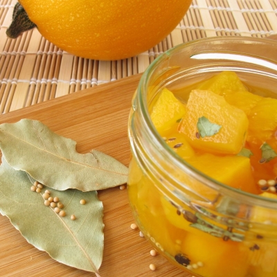 a canning jar of Sweet Pickled Squash garnished with bay leaves